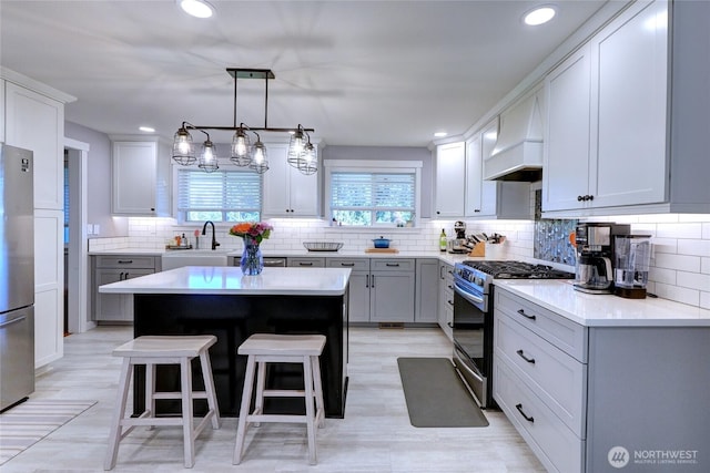 4204 Arbordale Ave W, University Place, WA 98466 - kitchen with stainless steel appliances, custom range hood, a sink, a kitchen breakfast bar, and backsplash