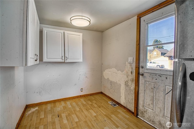 laundry area with light wood finished floors, visible vents, and baseboards