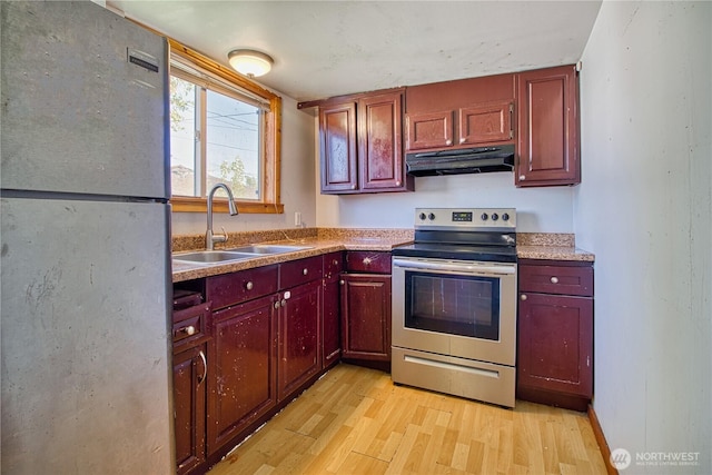 kitchen featuring a sink, freestanding refrigerator, stainless steel range with electric cooktop, under cabinet range hood, and light wood-style floors