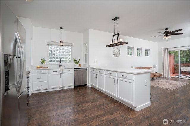 kitchen featuring light countertops, stainless steel appliances, white cabinetry, a peninsula, and dark wood-type flooring