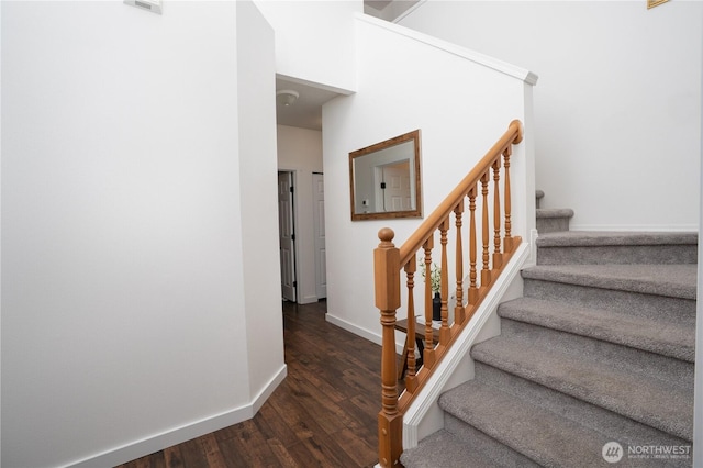 stairs featuring baseboards, wood finished floors, and a high ceiling