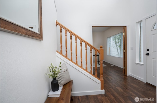 foyer featuring baseboards, stairs, and wood finished floors
