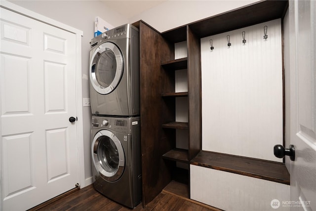 laundry area featuring dark wood-style flooring, stacked washer and dryer, and laundry area