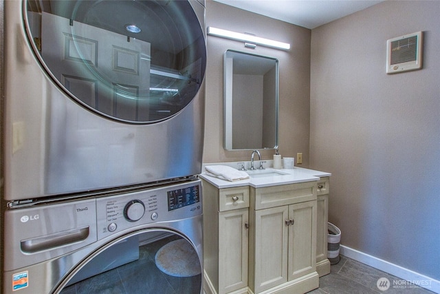 laundry area featuring a sink, laundry area, stacked washer / drying machine, tile patterned floors, and baseboards