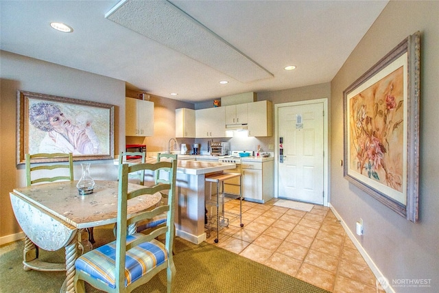 kitchen with baseboards, light countertops, recessed lighting, and white gas stove