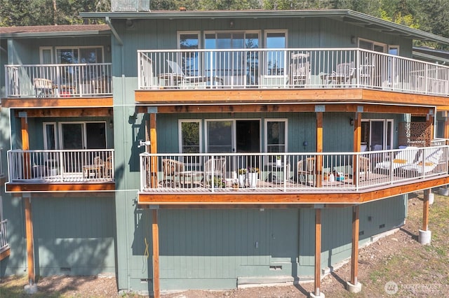 rear view of property with crawl space and a balcony