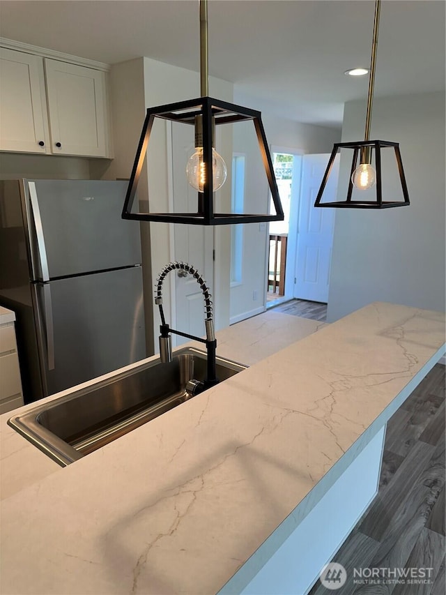 kitchen with decorative light fixtures, a sink, white cabinets, and freestanding refrigerator