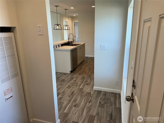 hallway featuring dark wood-type flooring, a sink, baseboards, and a heating unit