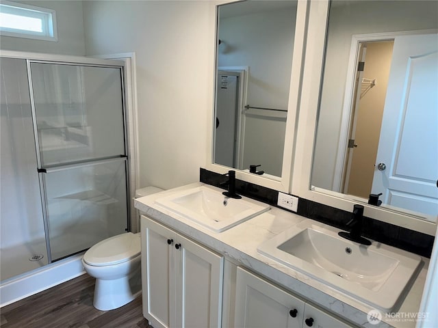 bathroom with toilet, a sink, a shower stall, and wood finished floors