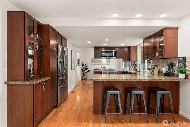 15510 NE 59th St, Redmond, WA 98052 - kitchen featuring a peninsula, baseboards, light wood-style floors, glass insert cabinets, and appliances with stainless steel finishes