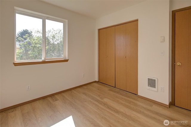 unfurnished bedroom with visible vents, light wood-type flooring, baseboards, and a closet