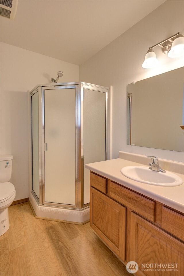 full bathroom with wood finished floors, toilet, a stall shower, and vanity