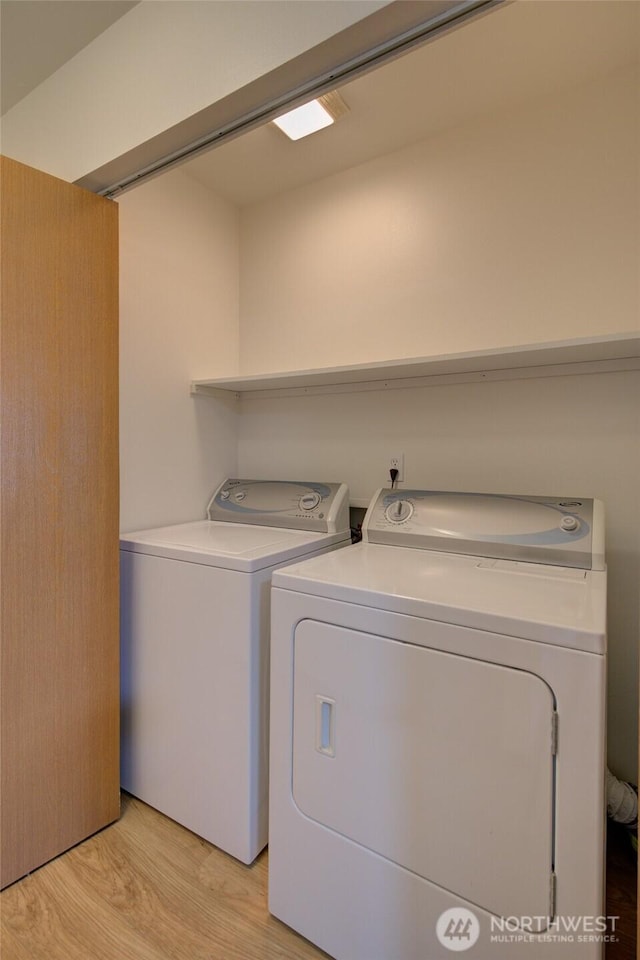 laundry area with washing machine and clothes dryer, laundry area, and light wood finished floors