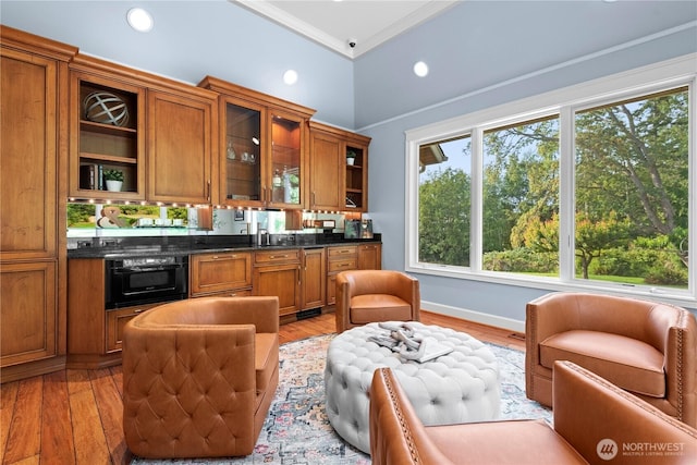 kitchen with black oven, brown cabinetry, and light wood-type flooring