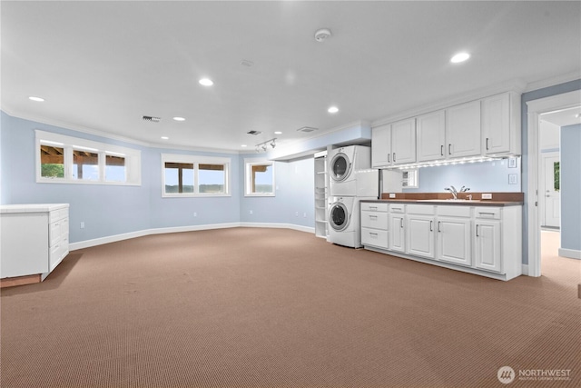 clothes washing area featuring baseboards, stacked washer / drying machine, and light colored carpet