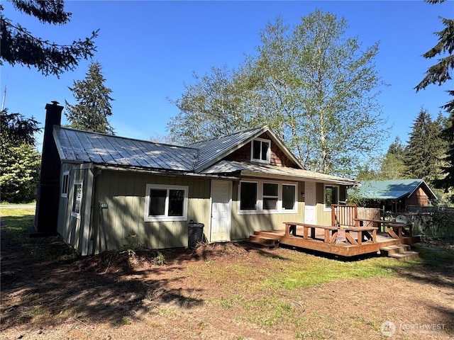 back of property with a chimney, a standing seam roof, a deck, and metal roof