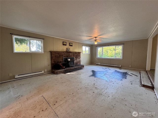 unfurnished living room featuring a baseboard heating unit, a ceiling fan, a wood stove, and a textured ceiling