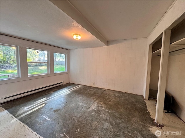 unfurnished bedroom with baseboard heating and wood walls
