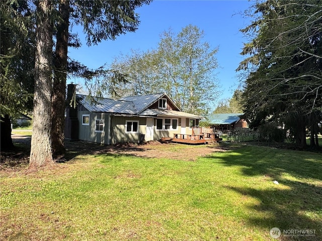 back of property featuring a yard, metal roof, and a deck