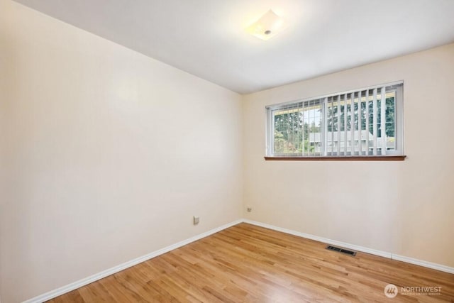 spare room featuring baseboards, light wood finished floors, and visible vents