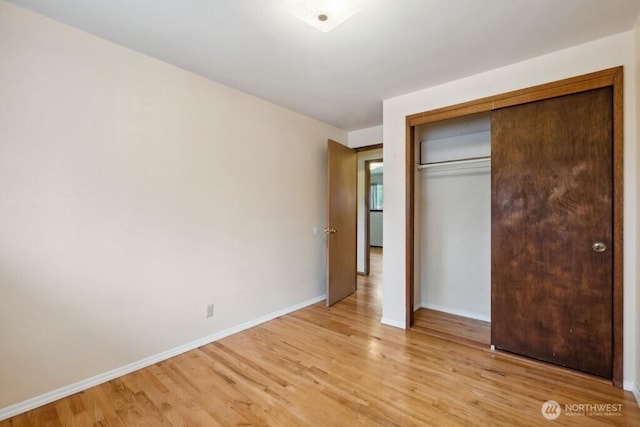 unfurnished bedroom with a closet, baseboards, and light wood-type flooring