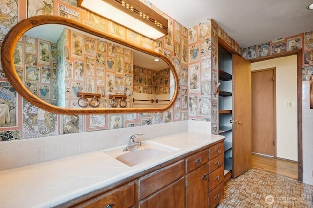 bathroom featuring vanity, decorative backsplash, and wallpapered walls