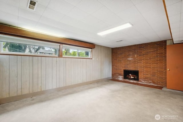 unfurnished living room with a fireplace, wood walls, and visible vents