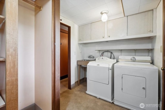 washroom with cabinet space, baseboards, and washing machine and clothes dryer