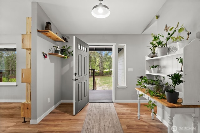 doorway with baseboards and light wood-style flooring