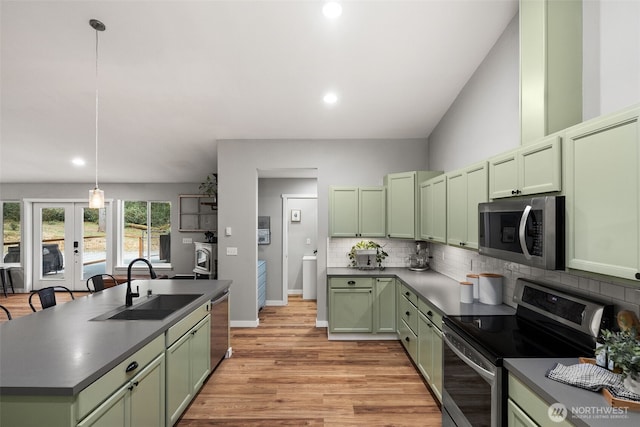 kitchen featuring appliances with stainless steel finishes, dark countertops, tasteful backsplash, a sink, and green cabinetry