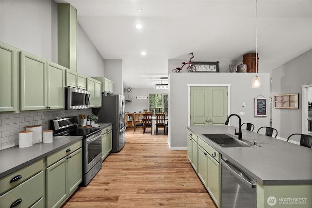 kitchen featuring stainless steel appliances, green cabinetry, a sink, and light wood-type flooring