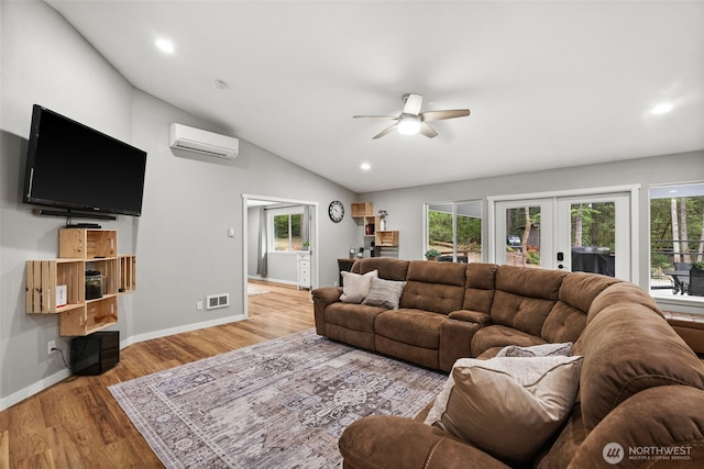 living area featuring a healthy amount of sunlight, ceiling fan, french doors, visible vents, and a wall mounted AC
