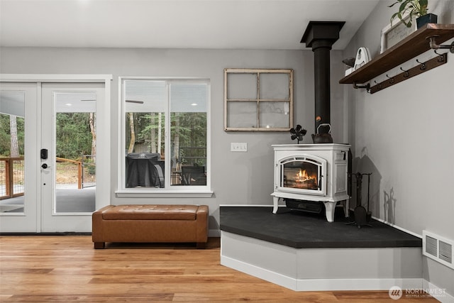 living room featuring baseboards, visible vents, wood finished floors, and a wood stove