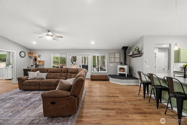 living room with a ceiling fan, french doors, a wood stove, light wood-type flooring, and recessed lighting