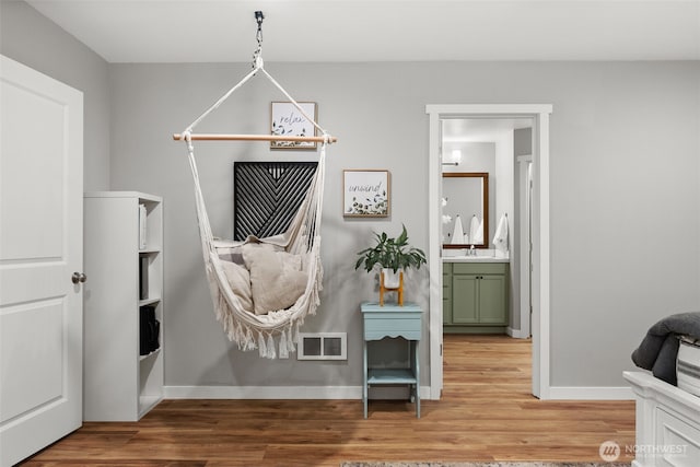 interior space featuring visible vents, a sink, baseboards, and wood finished floors