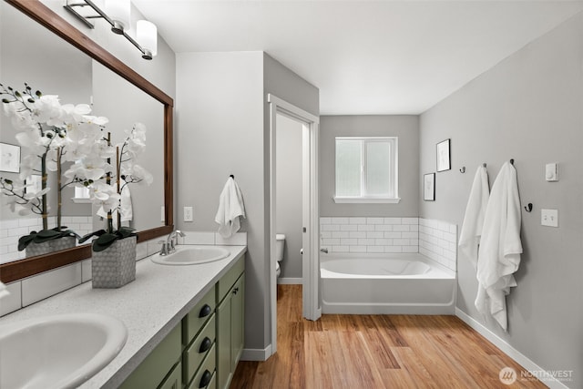 full bathroom with baseboards, a sink, wood finished floors, and toilet