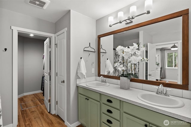 bathroom with visible vents, a sink, wood finished floors, and double vanity