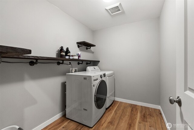 washroom featuring laundry area, baseboards, wood finished floors, visible vents, and washing machine and dryer