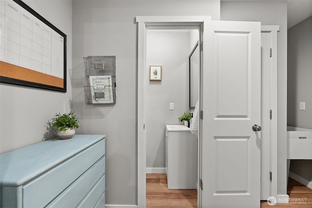bathroom with a sink, baseboards, and wood finished floors