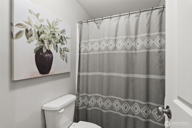full bath with a shower with shower curtain and toilet