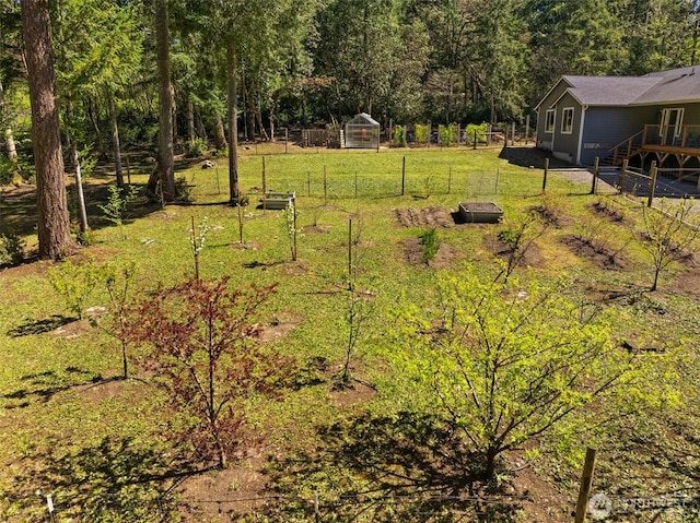 view of yard with an exterior structure, fence, an outbuilding, and a wooded view