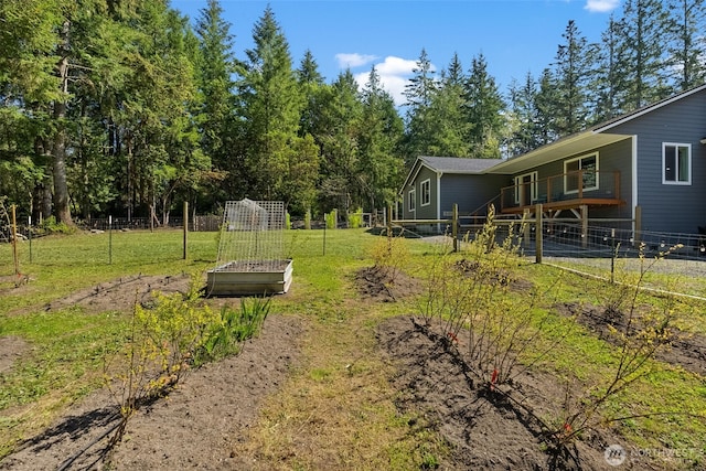 view of yard featuring fence, a balcony, and a vegetable garden