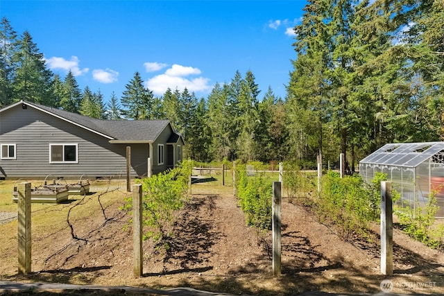 view of yard with an outdoor structure, a garden, and a greenhouse