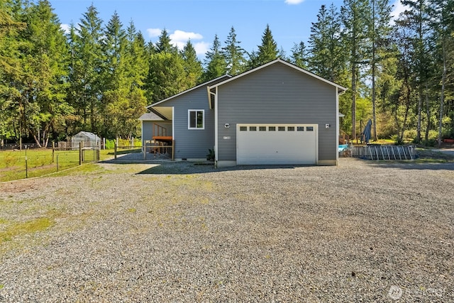 view of property exterior featuring a garage, fence, and gravel driveway