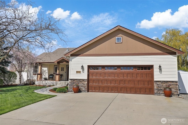 view of front of property with concrete driveway, a front lawn, stone siding, and covered porch