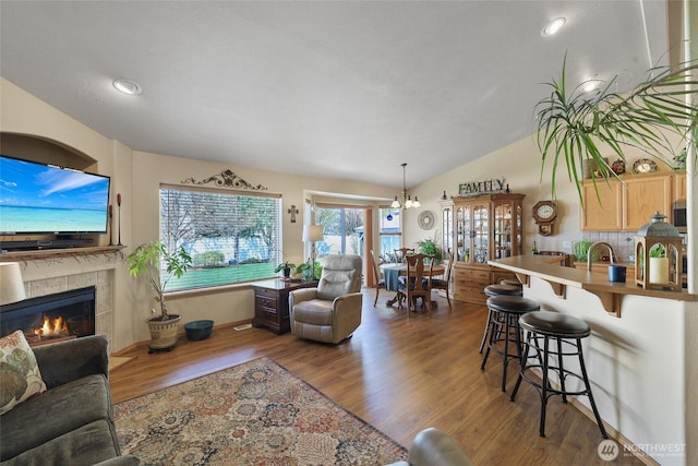 living room with recessed lighting, lofted ceiling, a tiled fireplace, and dark wood-style flooring