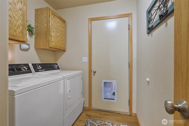 laundry room featuring washing machine and dryer, light wood-style floors, and cabinet space