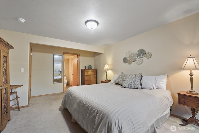 bedroom with ensuite bathroom, baseboards, and light colored carpet