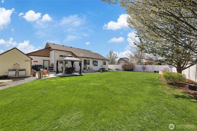 rear view of house with a fenced backyard, a gazebo, a patio, and a lawn
