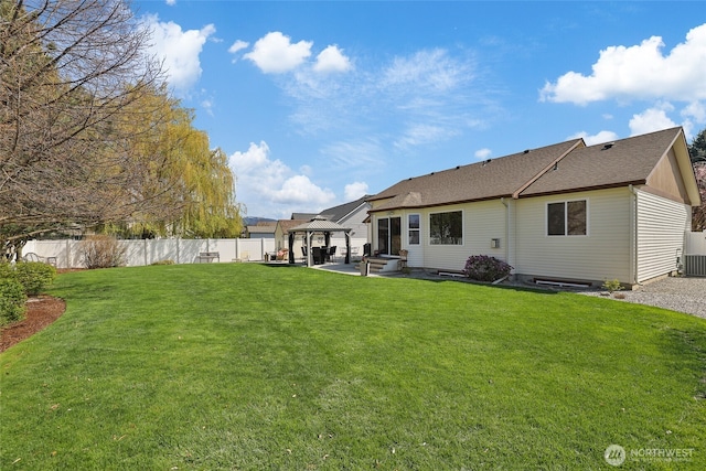rear view of property featuring a gazebo, a lawn, a shingled roof, a fenced backyard, and a patio